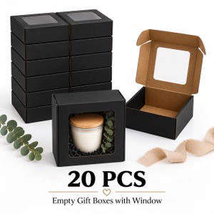 May include: A set of 20 black cardboard gift boxes with clear display windows. The boxes feature a matte black exterior and a natural brown interior. One box is shown open, and another contains a white candle with a wooden lid and greenery.