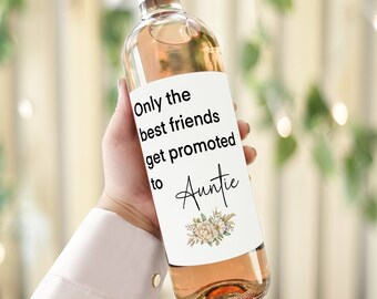 May include: A white wine bottle with a label that reads "Only the best friends get promoted to Auntie" with a floral design.