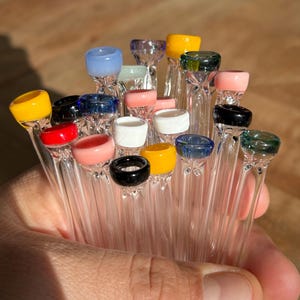 Puede incluir: Una colecci&oacute;n de pipas para fumar de vidrio con puntas de vidrio de colores. Las puntas son de varios colores, incluyendo amarillo, rojo, azul, verde y rosa.