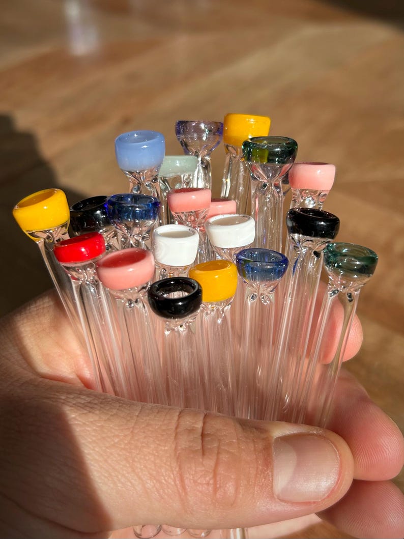 Puede incluir: Una colecci&oacute;n de pipas para fumar de vidrio con puntas de vidrio de colores. Las puntas son de varios colores, incluyendo amarillo, rojo, azul, verde y rosa.