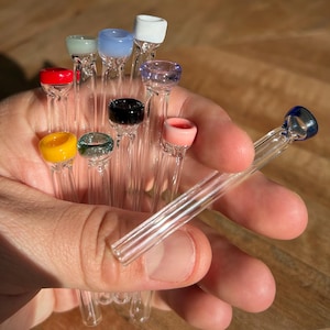 Puede incluir: Una colección de pipas para fumar de vidrio con puntas de vidrio de colores. Las puntas son de varios colores, incluyendo rojo, amarillo, verde, azul, rosa y blanco.