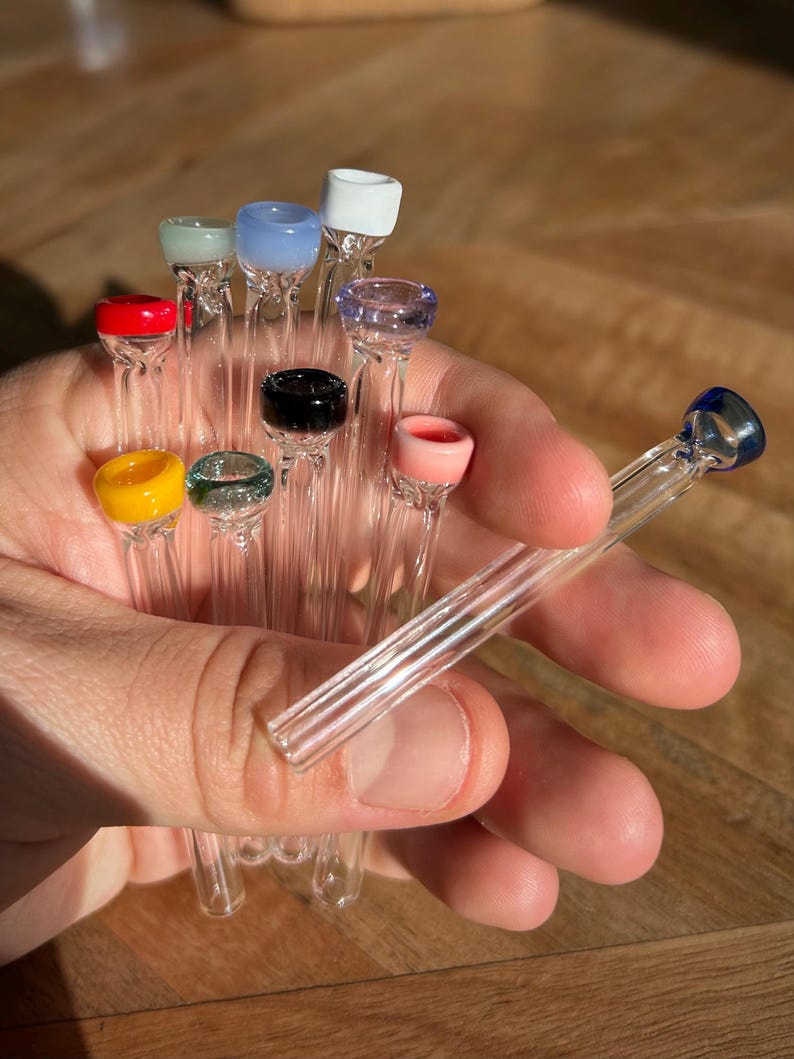 Puede incluir: Una colecci&oacute;n de pipas para fumar de vidrio con puntas de vidrio de colores. Las puntas son de varios colores, incluyendo rojo, amarillo, verde, azul, rosa y blanco.