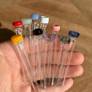 Puede incluir: Una colecci&oacute;n de 12 pipas para fumar de vidrio con puntas de vidrio de colores. Las puntas son de varios colores, incluyendo rojo, amarillo, verde, azul, rosa y blanco.