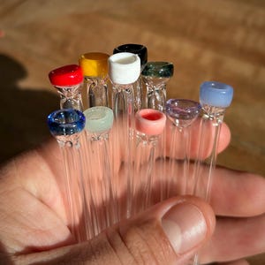 Puede incluir: Una colecci&oacute;n de diez pipas para fumar de vidrio con puntas de vidrio de colores. Las puntas son rojas, amarillas, blancas, negras, verdes, moradas, azules, azules claras, rosas y verdes claras.