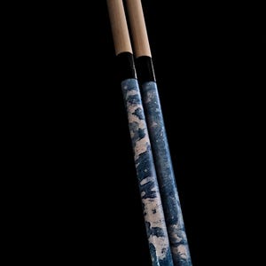 May include: Two wooden drumsticks with a blue and white marbled design. The drumsticks have black tape near the top.