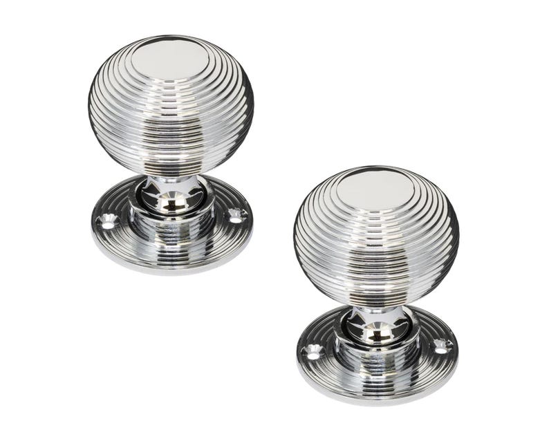 K&ouml;nnte beinhalten: Zwei polierte T&uuml;rkn&ouml;pfe aus Chrom. Jeder Knopf hat ein kugelf&ouml;rmiges Design mit konzentrischen Rillen und einer kreisf&ouml;rmigen Basis. Die Kn&ouml;pfe sind gl&auml;nzend und reflektierend, f&uuml;r Inneneinrichtung.