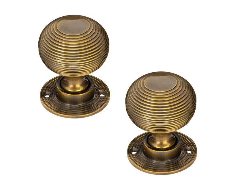 K&ouml;nnte beinhalten: Zwei antike T&uuml;rkn&ouml;pfe aus Messing. Jeder Knopf hat eine kugelf&ouml;rmige Form mit konzentrischen Rillen, die auf einer kreisf&ouml;rmigen Basis montiert sind. Das Messing hat eine warme, gealterte Patina, die auf Vintage-Hardware hindeutet.