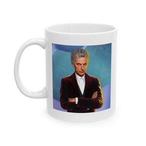 May include: White ceramic mug with a colorful illustration of a man with gray hair wearing a burgundy suit jacket and a white shirt. The background is a blue and purple abstract design.