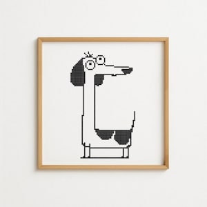 May include: A framed cross-stitch art piece featuring a whimsical dog design. The dog is depicted in black and white, wearing sunglasses, with a long neck and a surprised expression. The artwork is set against a white background.