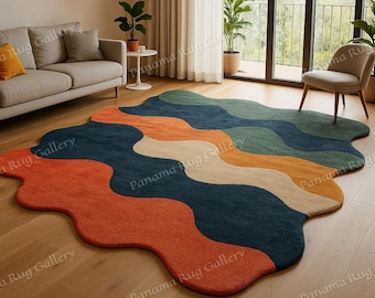 May include: A colorful, abstract area rug with a unique, flowing design. The rug features wavy sections of orange, navy blue, green, beige, and yellow. The rug is placed on a hardwood floor in a living room setting.