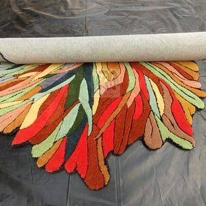 Pode incluir: Um tapete abstrato colorido com uma forma org&acirc;nica &uacute;nica. O tapete &eacute; feito de um material macio e felpudo e apresenta uma variedade de cores, incluindo vermelho, laranja, amarelo, verde, azul e marrom.