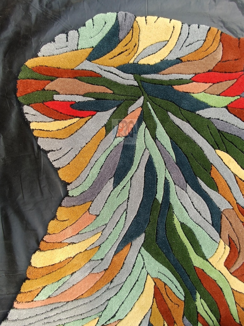 Pode incluir: Tapete de &aacute;rea abstrato com um design colorido e em camadas que apresenta tons de verde, azul, amarelo, laranja, vermelho e cinza. O tapete tem uma forma &uacute;nica e org&acirc;nica.