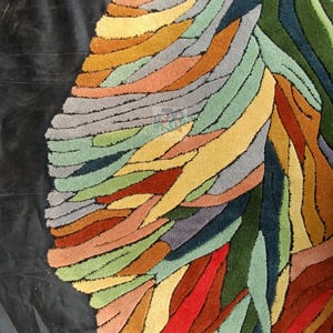 Pode incluir: Um tapete abstrato colorido com um design de formas sobrepostas e em camadas em tons de verde, azul, vermelho, laranja, amarelo e marrom.