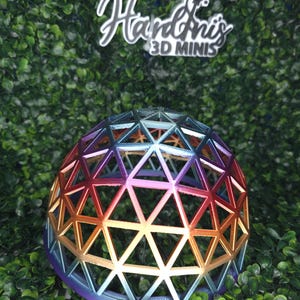 May include: A 3D-printed geometric dome with a rainbow gradient of colors, including orange, yellow, blue, and purple. The dome is composed of interconnected triangles. The logo "Hardini's 3D Minis" is visible in the background.