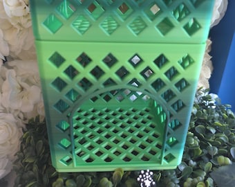 Puede incluir: Una caja de almacenamiento cuadrada de parte superior abierta con un patrón de celosía en todos los lados y la base. La caja muestra una transición de color degradado desde un verde lima claro en la parte inferior hasta un verde bosque oscuro en el borde superior. Un pequeño letrero negro dice Hardinis 3D Minis.