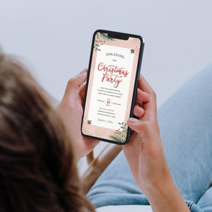 May include: A person is looking at a smartphone screen displaying a Christmas party invitation with a pink background and green and red floral accents. The invitation text reads "Einladung zur Christmas Party".
