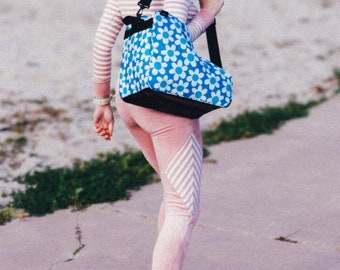 May include: A person wearing pink and white striped pants and yellow roller skates is carrying a blue and white floral tote bag with a black strap.