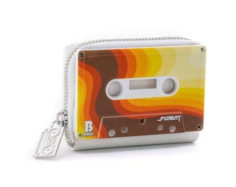 May include: A white cassette tape-shaped wallet with a zipper closure and a silver boombox charm. The wallet features a retro design with brown, orange, and yellow stripes. The text "B Sides" and "FYDELITY" are visible on the wallet.