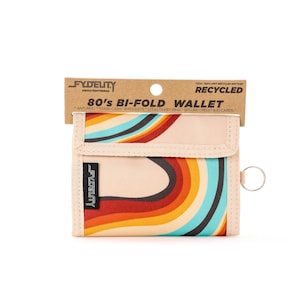 Könnte beinhalten: Beige Bi-Fold-Geldbörse mit Retro-Regenbogen-Design. Die Geldbörse trägt den Text "80's BI-FOLD WALLET" und das Branding "FYDELITY". Sie enthält einen Schlüsselring und besteht aus recycelten Materialien.
