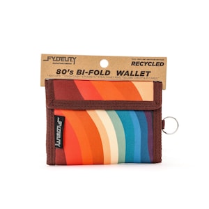 May include: A bi-fold wallet with a retro 80s design. The wallet features a rainbow stripe pattern in shades of orange, red, yellow, green, and blue. It has a brown border and a metal key ring. The wallet is made from recycled materials.