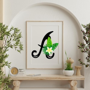 Puede incluir: Una letra A negra con una flor blanca y hojas verdes sobre un fondo blanco. La letra está en una fuente cursiva.