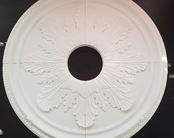 Könnte beinhalten: Eine weiße Deckenrosette mit einem dekorativen floralen Design. Die Rosette ist aus Gips gefertigt und soll als dekoratives Element in einer Decke verwendet werden.