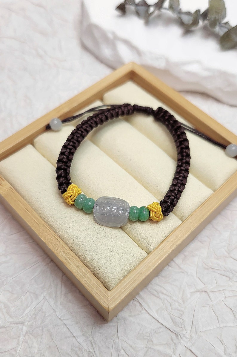Peut inclure: Un bracelet tress&eacute; marron avec un charme en perles de jade vert et jaune. Le bracelet est pr&eacute;sent&eacute; dans une bo&icirc;te en bois.
