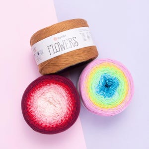 May include: Three skeins of yarn in various colors. One is brown with a white label that reads "FLOWERS". Another is a gradient of red to white. The third is a gradient of pink, yellow, green, and blue.