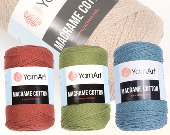 May include: A collection of YarnArt Macrame Cotton yarn in various colors. The image shows rolls of yarn in shades of beige, rust, olive green, and teal blue. Each roll has a label with the brand name and product information.