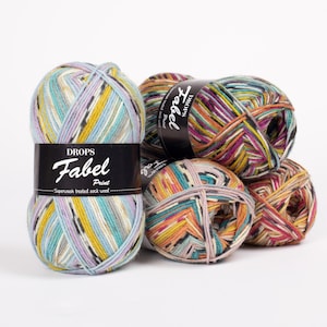 Puede incluir: Cuatro ovillos de lana de colores con una etiqueta negra que dice "DROPS Fabel Print - Superwash treated sock wool"