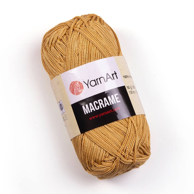 Mustard color yarn skein in white background. 100% polyester yarn. YarnArt macrame cord.