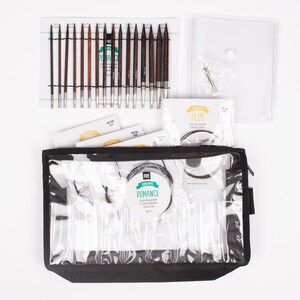 May include: A set of interchangeable circular knitting needles in a black zippered case. The needles are made of wood and have a silver metal tip. The set includes a variety of sizes, from 2.5 mm to 8 mm. The case also includes a needle gauge and a set of cable connectors. The set is labeled "DROPS Romance Interchangeable Circular Needles Deluxe Set - Birch".