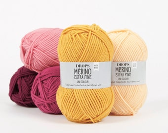 May include: Four balls of yarn in different colors: pink, burgundy, yellow, and peach. The yarn is labeled "DROPS MERINO EXTRA FINE UNI COLOUR" and is made of 100% wool.