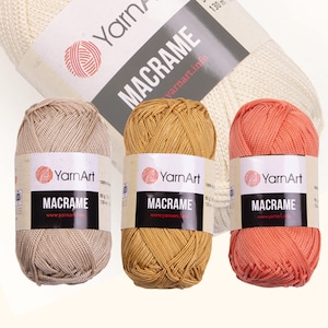 Three diferent color yarn skein in white background. 100% polyester yarn. Skeins color is: beige, mustard and pink. YarnArt macrame cord.