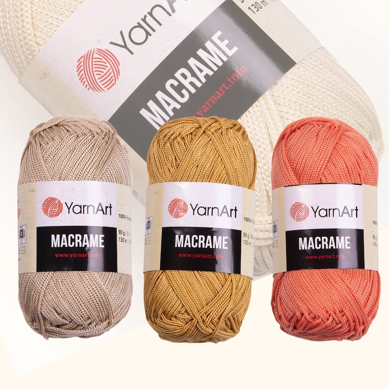 Three diferent color yarn skein in white background. 100% polyester yarn. Skeins color is: beige, mustard and pink. YarnArt macrame cord.