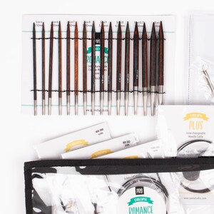 May include: A set of interchangeable knitting needles in a black zippered case. The needles are made of wood and metal and come in a variety of sizes. The case also includes a set of cable needles. The needles are labeled "DROPS PRO ROMANCE" and "DROPS PLUS".