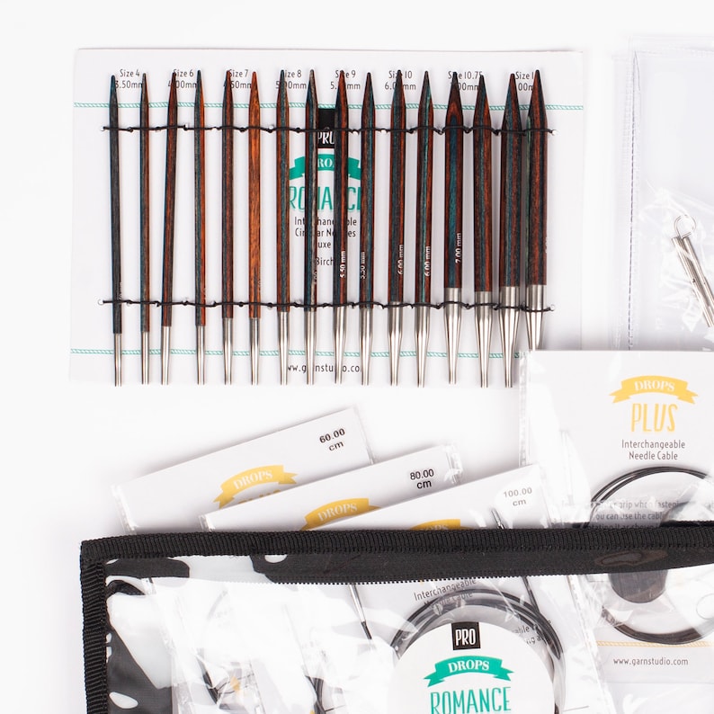 May include: A set of interchangeable knitting needles in a black zippered case. The needles are made of wood and metal and come in a variety of sizes. The case also includes a set of cable needles. The needles are labeled "DROPS PRO ROMANCE" and "DROPS PLUS".