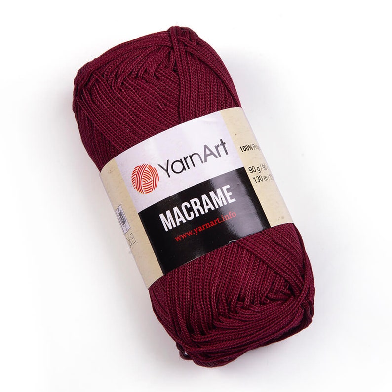 Burgundy color yarn skein in white background. 100% polyester yarn. YarnArt macrame cord.