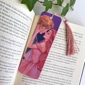 May include: A bookmark featuring a romantic illustration of a couple embracing, with a pink tassel. The artwork depicts a man and woman in a tender moment, set against a starry purple background. The bookmark is placed on an open book.