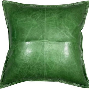 Puede incluir: Una almohada de cuero verde con un diseño cuadrado. La almohada tiene un aspecto desgastado sutil y una textura suave y flexible.