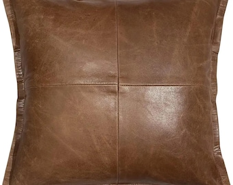 May include: A brown leather pillow with a square design. The pillow has a stitched border and a soft, textured surface.
