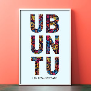 May include: A white framed print with the word "UBUNTU" in large, bold, white letters. The letters are filled with colorful, geometric patterns. The text "I AM BECAUSE WE ARE." is printed below the word "UBUNTU".