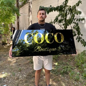 May include: A black sign with gold lettering that reads "Coco Boutique".