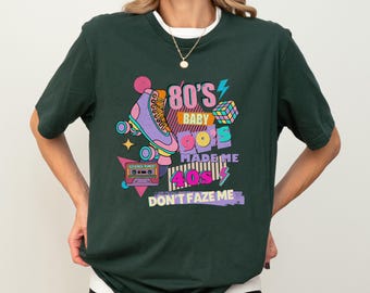 May include: A forest green t-shirt with a retro graphic design featuring a roller skate, a cassette tape, and the text "80's Baby 90's Made Me 40's Don't Faze Me".