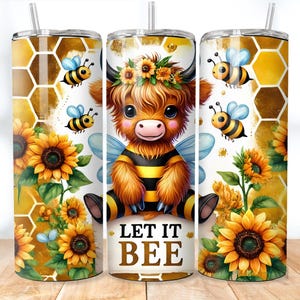 May include: A white tumbler with a cartoon highland cow wearing a bee costume and a sunflower design. The tumbler has the text "Let it Bee" on the front.