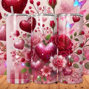 May include: Three pink and red stainless steel tumblers with a Valentine's Day theme. The tumblers feature a design of red roses, hearts, and butterflies on a pink and white background.