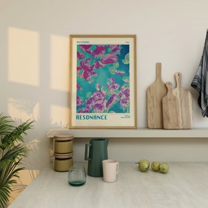 K&ouml;nnte beinhalten: Ein gerahmtes Poster mit einem t&uuml;rkisfarbenen Hintergrund und rosa und violetten quallenartigen Formen. Das Poster tr&auml;gt den Text "Aura Series" und "RESONANCE" in Wei&szlig;. Das Poster h&auml;ngt an einer wei&szlig;en Wand &uuml;ber einem Regal mit einem Holzbrett und einem Keramik-Krug.