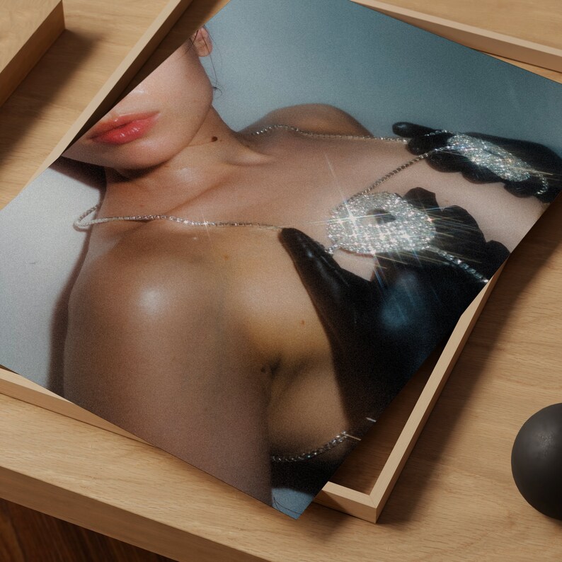 Op de afbeelding: Een close-up van de borst van een vrouw met een diamant-versierde ketting met hanger. De hanger heeft de vorm van een hart en wordt vastgehouden in een handschoen.