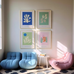 K&ouml;nnte beinhalten: Ein Wohnzimmer mit vier gerahmten Drucken von abstrakten Blumenmustern in Blau, Gr&uuml;n, Rosa und Gelb. Es gibt drei blaue und rosa Sessel und einen kleinen wei&szlig;en Tisch mit einem Stapel B&uuml;cher darauf.