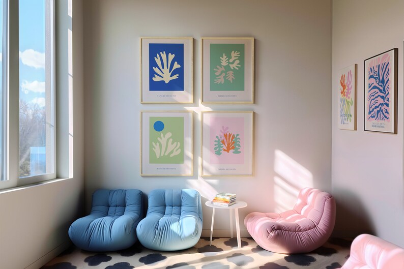 K&ouml;nnte beinhalten: Ein Wohnzimmer mit vier gerahmten Drucken von abstrakten Blumenmustern in Blau, Gr&uuml;n, Rosa und Gelb. Es gibt drei blaue und rosa Sessel und einen kleinen wei&szlig;en Tisch mit einem Stapel B&uuml;cher darauf.